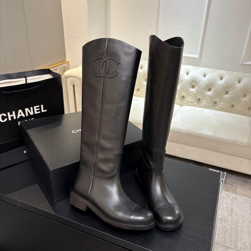Chanel CC logo knee-high black leather riding boots displayed with original Chanel box, dust bag, and shopping bag